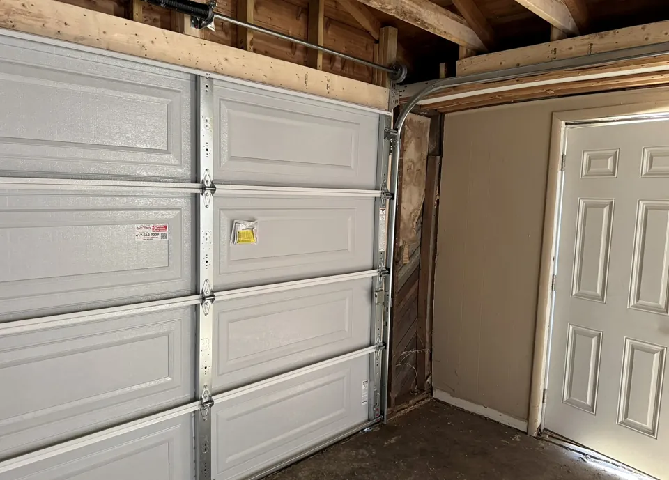 The garage door tracks, ceiling framing, and side entry.